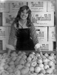 Lorelei Flemming behind a large display of Delicious apples at the Twin Hill Farm, about 1970