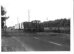 Southern Pacific/North Western Pacific railroad train pulling two cars and a caboose adjacent to Gravenstein Highway North at Joyce Drive, 1940s or 1950s