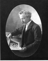 Portrait photo of Luther Burbank, sitting looking at album or magazine, about 1900