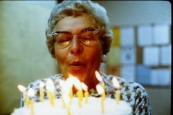 Unidentified older woman blowing out candles on a birthday cake