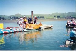 Chili pepper float and 'No Farmed Fish' float of US Fish and Wildlife and craft in shallow water of Bodega Bay at the Fisherman's Festival in Bodega Bay, 1995