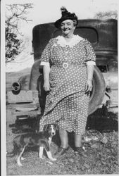 Lucy M. Pearson Narron Crabtree, standing behind a car with a black puppy at her feet, about 1930s