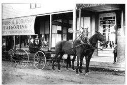 J.P. McDonell, publisher of the 'Sebastopol Times' and Clyde Berry driving in front of the Swords & Robinson Tailoring Shop on Main Street, Sebastopol, California