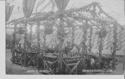 1911 Gravenstein Apple Show display by Healdsburg California show three men standing behind a table covered in fruit and apples