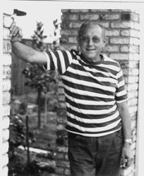 Harold Narron standing by a brick pillar with a garden in the background, about 1970