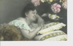 Postcard of a woman in Victorian dress and hairdo on a pillow with pigeon delivering letter