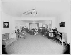 Interior of the Borba radio store with cabinet or console style radios and wicker chairs arranged around the room, 1920s