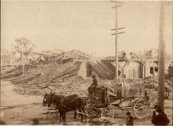 Man driving a wagon with a piano box in front of the ruins of a downtown Santa Rosa, California building after the 1906 earthquake