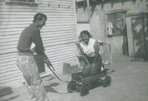 Man pulling his sister-in-law in a wagon, East Los Angeles, California