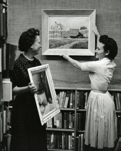 Eleanor Beyers and Bobbie Bison remove framed art from the walls of the Lancaster Library