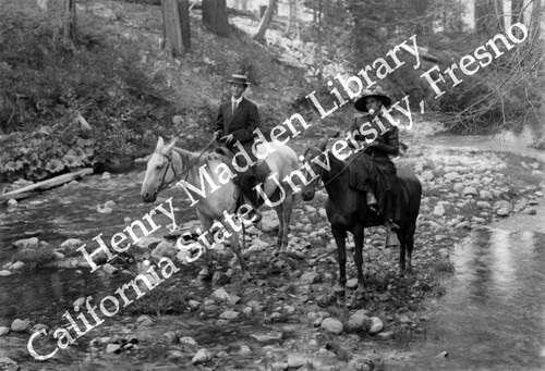 Woman and man on horseback standing in creek