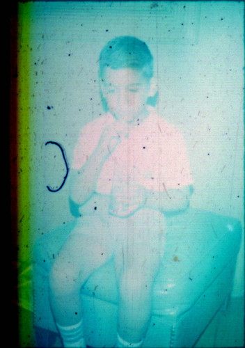 Unidentified young boy seated on an ottoman