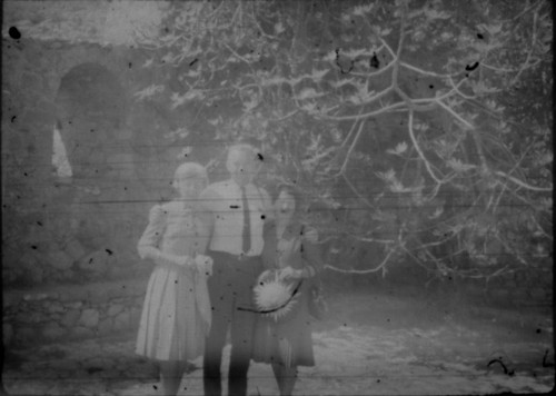 Alice Peters with unidentified couple standing in courtyard