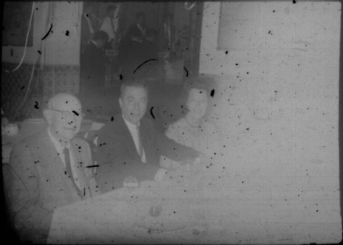 One unidentified woman and two unidentified men seated at a table