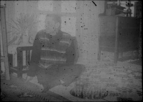 Unidentified man seated on floor of house