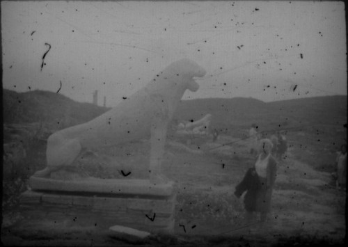 Unidentified woman standing next to lion sculpture