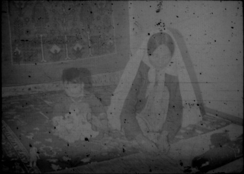 Unidentified woman and child in traditional clothing seated on a carpet