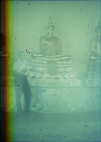 Unidentified man standing next to golden Buddha statue