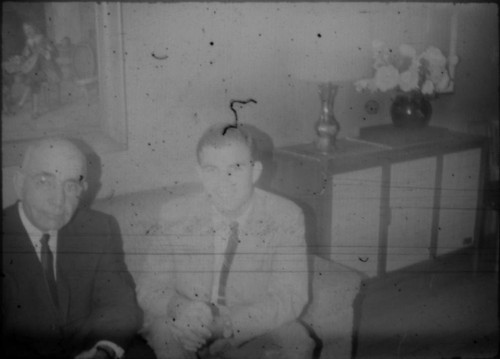 Leon Peters and unidentified man seated on a couch