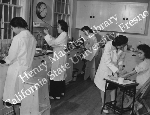 Four technicians and a blood-test patient in hospital laboratory at Granada Relocation Center