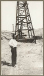 [Man standing near oil well]