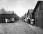 [Unidentified refugee camp. Children posing along rows of cottages]