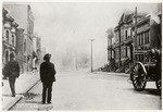 [Man in street watching fire burn. Unidentified location]