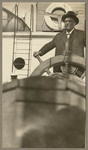 [Alfred Fuhrman posing at ship's wheel on the Admiral Dewey]