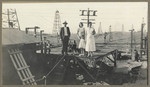 [Man and women with oil wells behind them]