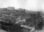 [Cityscape from above circa Kearny and Post Sts. looking northwest toward Nob Hill during reconstruction. Along California St. in distance: Fairmont Hotel, left; Grace Church, center; St. Mary's Church, right]