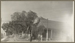 [Two men standing in driveway near house]