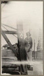 [Young woman standing at base of oil well]