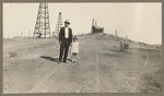 [Man and little girl in foreground, oil wells in background]