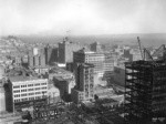 [Cityscape from above circa Kearny and Post Sts. looking northeast toward Wholesale District. Telegraph Hill in distance, left; Merchants' Exchange Building and Mills Building, center]