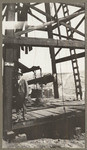 [Alfred Fuhrman standing at base of oil well with ladder seen on right]