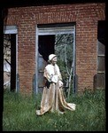 Girl in costume in front of ruined store in Coloma at the Centennial celebration in 1948 (2 views)