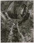 [Cowboy sitting on rocks next to low volume waterfall in Santa Barbara County]