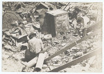 [Two men sifting through earthquake debris]