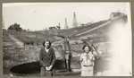 [Two women standing in front of open storage tank with pipeline leading into it]