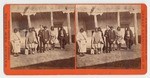 [American Indians and white man in suit standing in front of Adobe building]