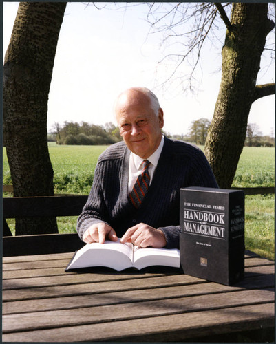 Charles Handy, color photo outside sitting with book