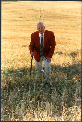 Charles Handy, color photo outside walking up hill with stick