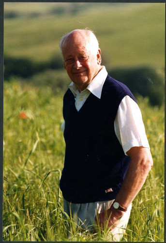 Charles Handy, outside photo standing in tall grass in vest