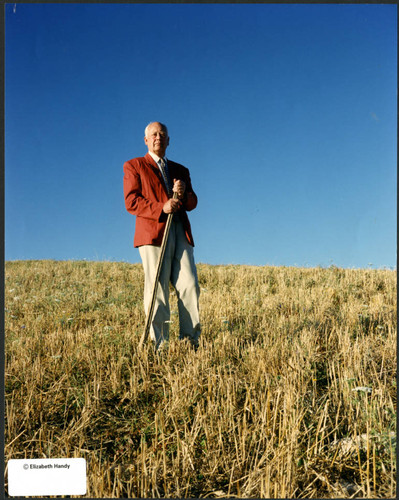 Charles Handy, color photo outside in field with stick