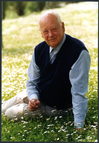 Charles Handy, outside photo in vest sitting and holding flowers