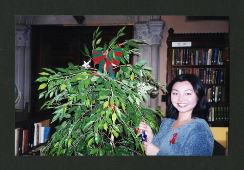 Scripps student smiles while decorating a Christmas tree in Denison Library, Scripps College
