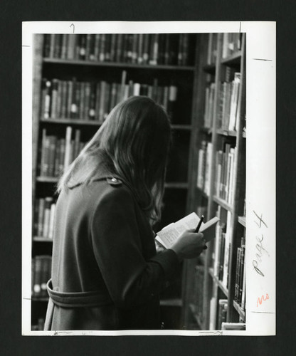 Scripps student reading amidst grand bookshelves in Denison Library, Scripps College