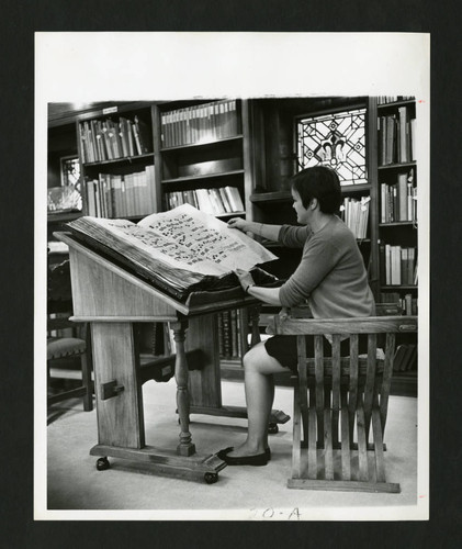 Scripps student turning the page of a 16th Century Gradual in Denison Library, Scripps College