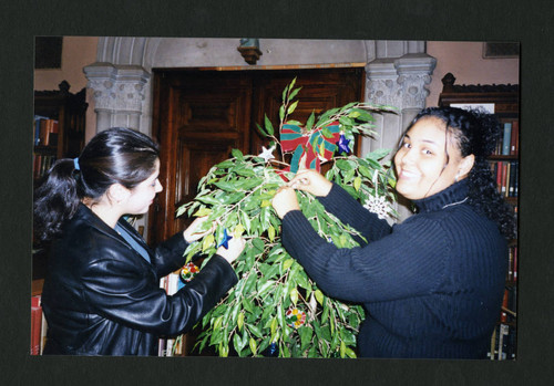 Two Scripps students working together to decorate Denison Library's Christmas tree, Scripps College