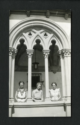 Three librarians smile, posing in an ornate archway, Scripps College